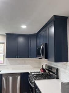 Blue kitchen cabinets with white countertops and backsplash